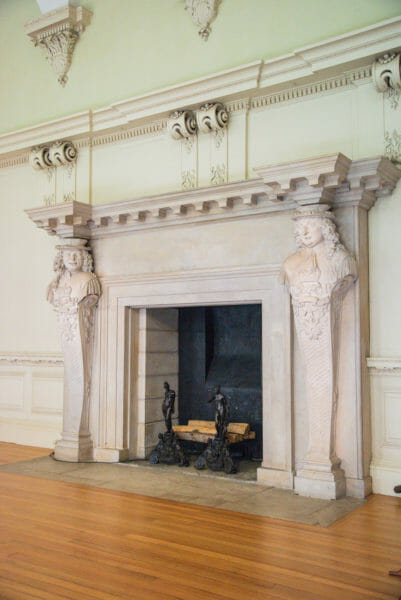 Historic white fireplace with busts of men engraved
