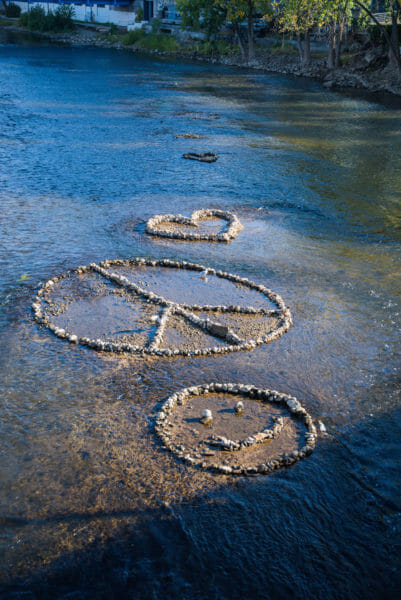 Peace sign and smiley face made out of rocks in river in Grand Rapids, MI