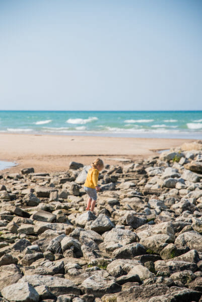Girl on rocks by beach in South Haven, Michigan