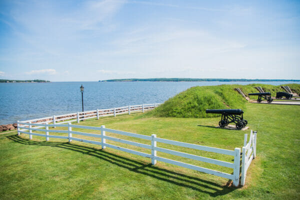 a fence and canons with a blue sky on Prince Edward Island